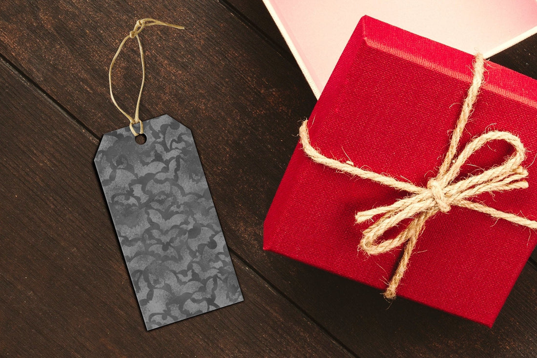 Gift tag with black bats next to a red box tied with twine