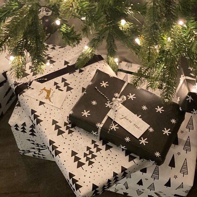 White wrapping paper with hand sketched christmas trees and stars under a Christmas tree
