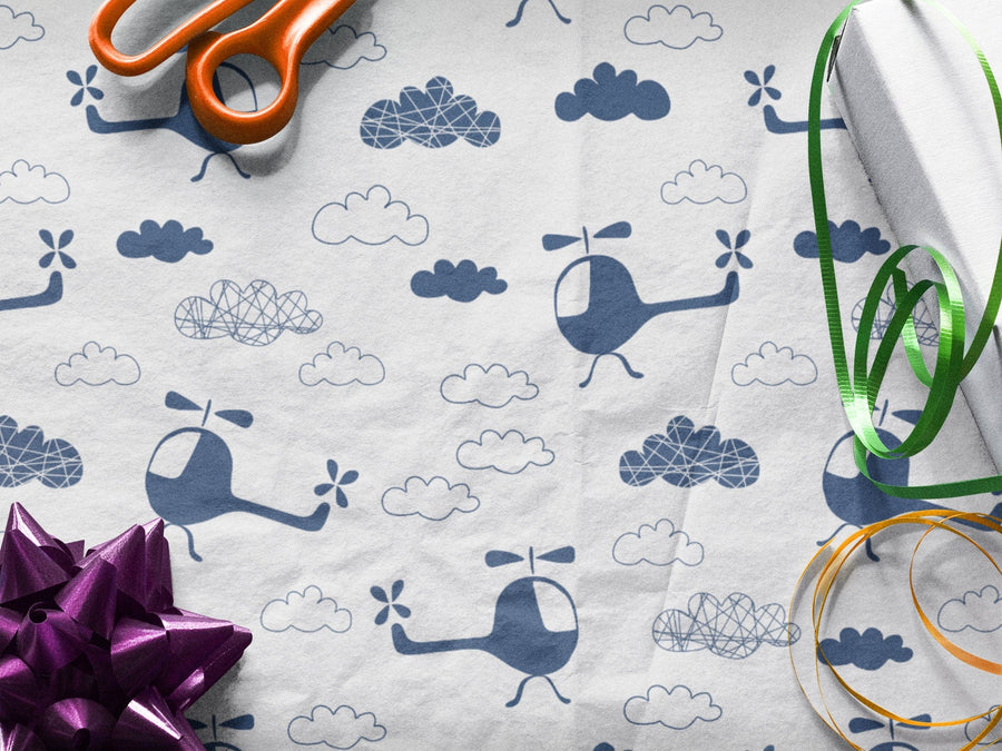 White Wrapping Paper Sheet with Blue Helicopters and Clouds. Ribbon, bow and scissors sitting on top 