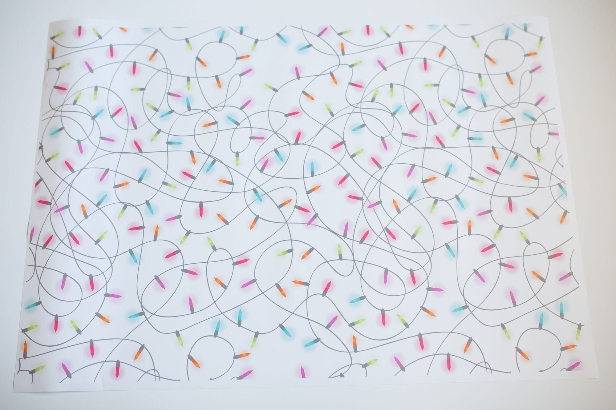 A White sheet of wrapping paper with Colorful Christmas Lights Tangled up